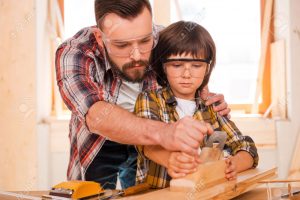 ۴۰۵۶۷۶۳۲-success-is-a-learnable-skill-concentrated-young-male-carpenter-teaching-his-son-to-work-with-wood-in-stock-photo